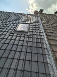 Toiture rénovée avec tuiles noires et fenêtre de toit neuve installée par Dépann’TOIT à Bruxelles.