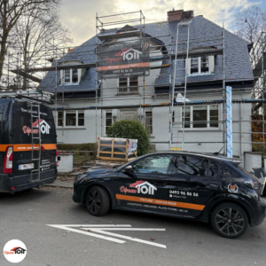 Chantier de rénovation de toiture Dépann’TOIT à Bruxelles avec échafaudage et véhicules de l’entreprise devant une maison en travaux